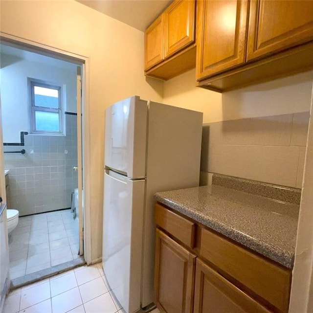 kitchen with light tile patterned flooring and white fridge