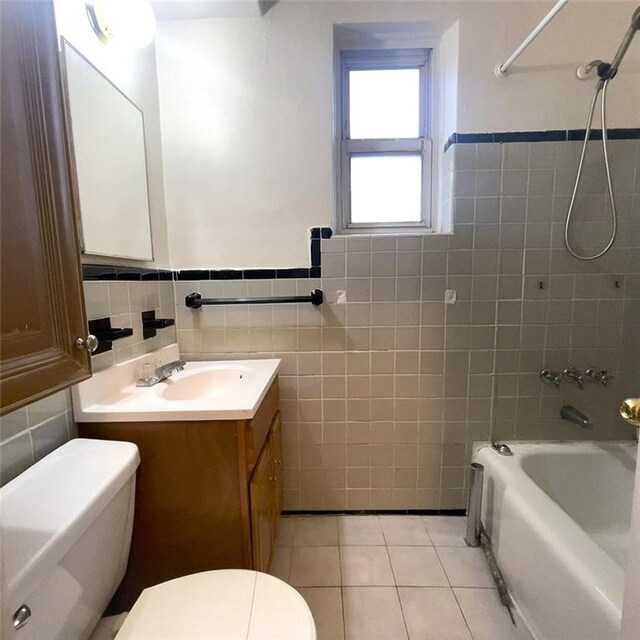 full bathroom featuring toilet, tiled shower / bath combo, tile walls, tile patterned floors, and vanity