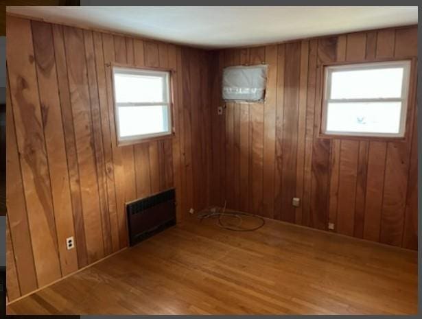 unfurnished room featuring hardwood / wood-style floors and wooden walls