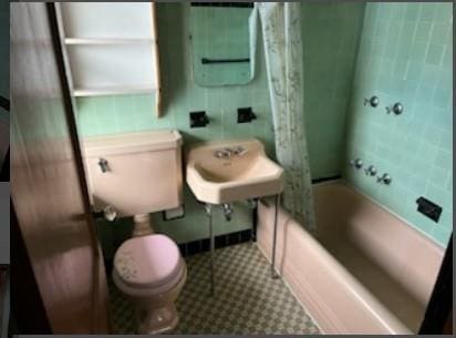 full bathroom with sink, shower / bath combination with curtain, tile walls, and toilet