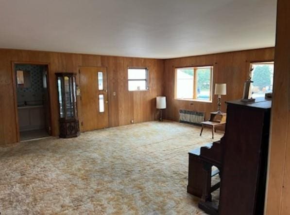 carpeted living room featuring radiator and wooden walls