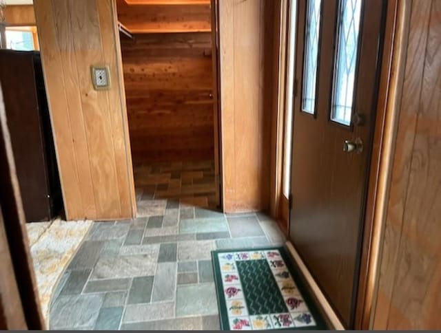 hall with plenty of natural light and wood walls