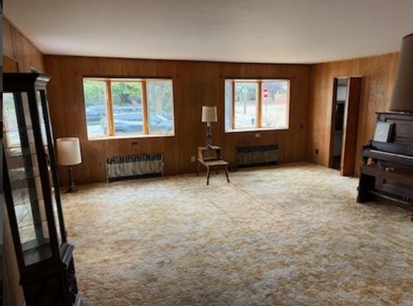 unfurnished living room featuring light carpet and radiator heating unit