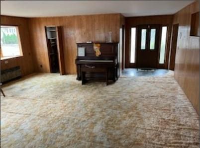 foyer featuring carpet and wood walls