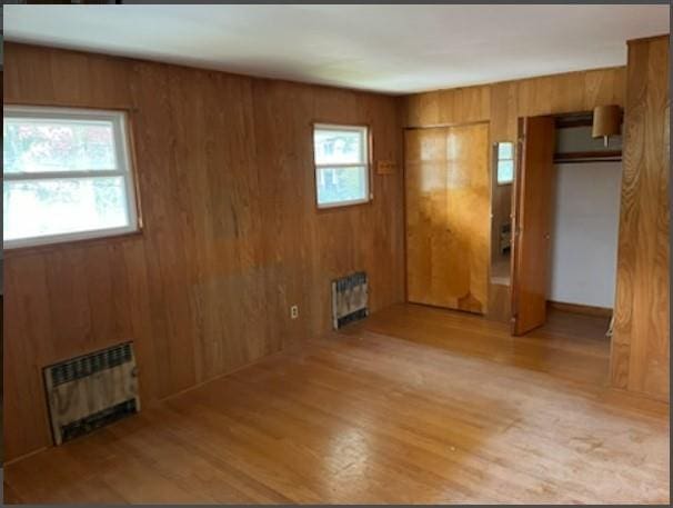 unfurnished room with wood walls, radiator, and light hardwood / wood-style flooring