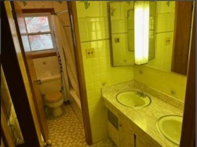 bathroom with a shower with shower curtain, toilet, and sink