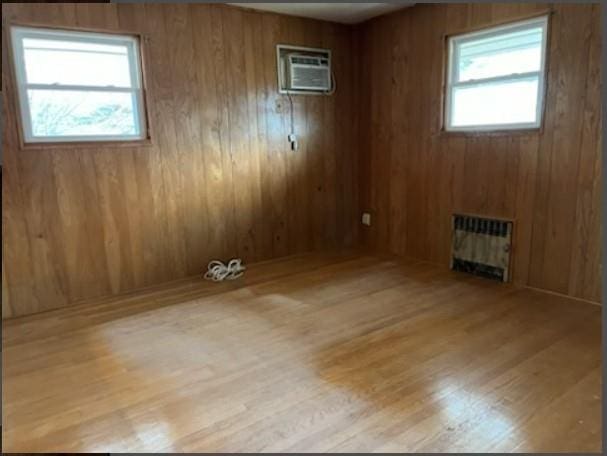 unfurnished room featuring radiator, wooden walls, and light wood-type flooring