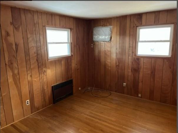 spare room featuring wooden walls, hardwood / wood-style flooring, and a wealth of natural light