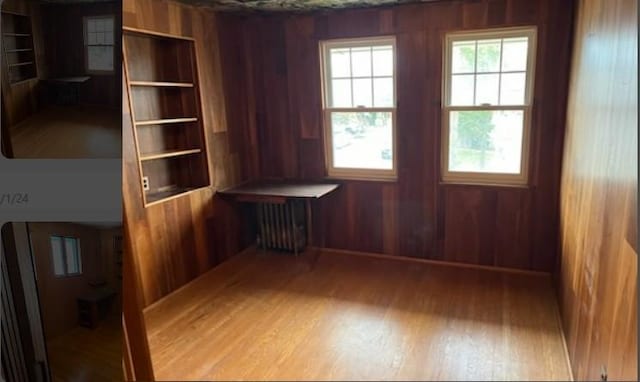 unfurnished room with light hardwood / wood-style flooring, built in features, radiator, and wooden walls