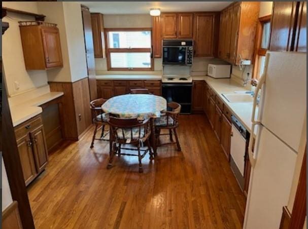 kitchen with wood walls, sink, wood-type flooring, and white appliances