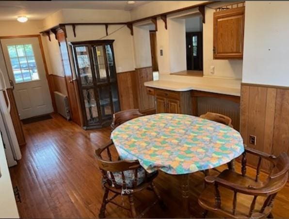 dining room featuring wood walls, radiator heating unit, and dark hardwood / wood-style floors