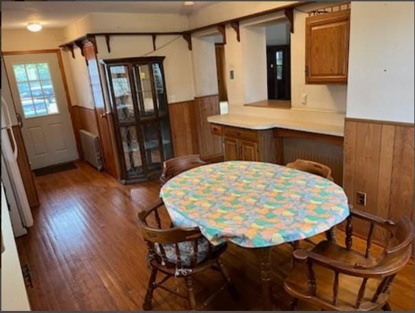 dining room with dark hardwood / wood-style floors, wood walls, and radiator