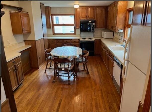 kitchen featuring wood-type flooring, white appliances, sink, and wooden walls