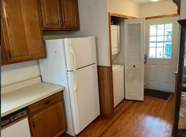 kitchen with stacked washer and dryer, hardwood / wood-style floors, and white appliances