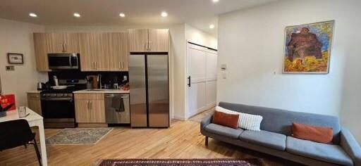 kitchen with backsplash, light brown cabinets, appliances with stainless steel finishes, and light wood-type flooring