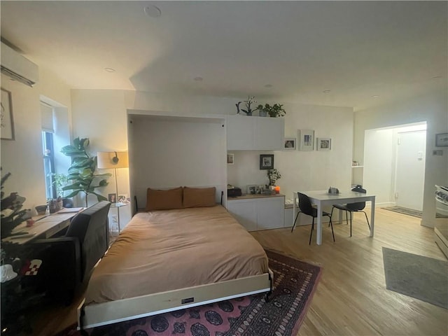 bedroom with a wall unit AC and light hardwood / wood-style flooring