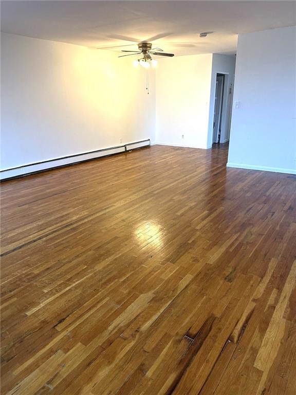 spare room featuring a baseboard radiator, dark hardwood / wood-style floors, and ceiling fan