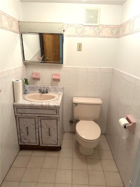 bathroom featuring vanity, tile walls, tile patterned floors, and toilet