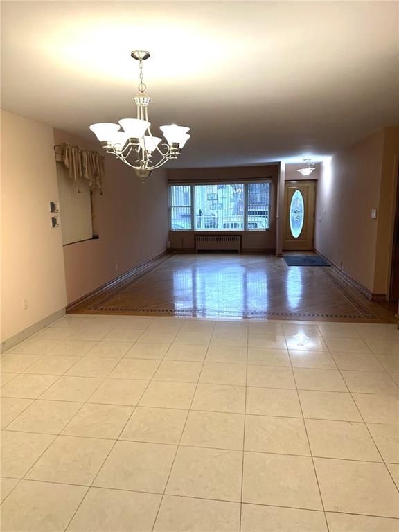 interior space featuring radiator heating unit and a chandelier