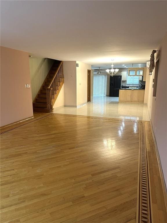 spare room featuring a notable chandelier and light wood-type flooring