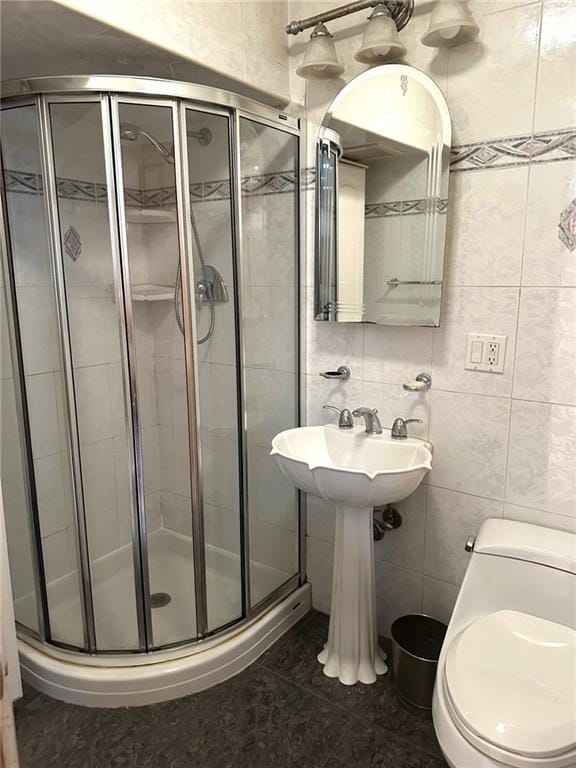 bathroom with toilet, a shower with shower door, tile patterned flooring, and tile walls