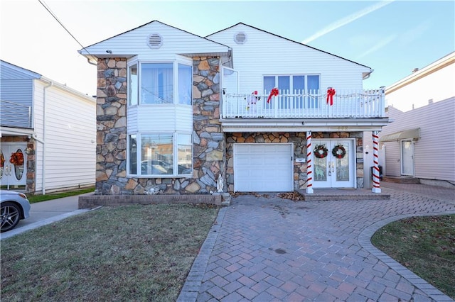 view of front of home featuring a garage, a balcony, and french doors