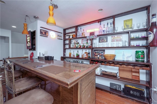 bar with hardwood / wood-style floors and decorative light fixtures