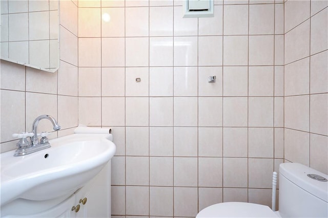 bathroom featuring vanity, toilet, and tile walls