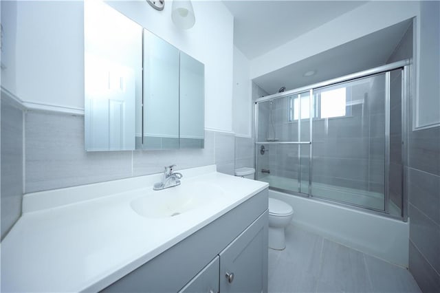 full bathroom with vanity, toilet, tile walls, and enclosed tub / shower combo