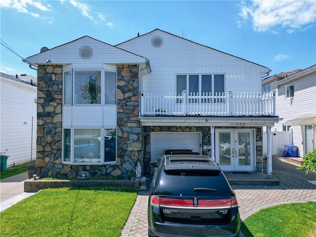 view of front of house featuring french doors, a balcony, a garage, and a front lawn