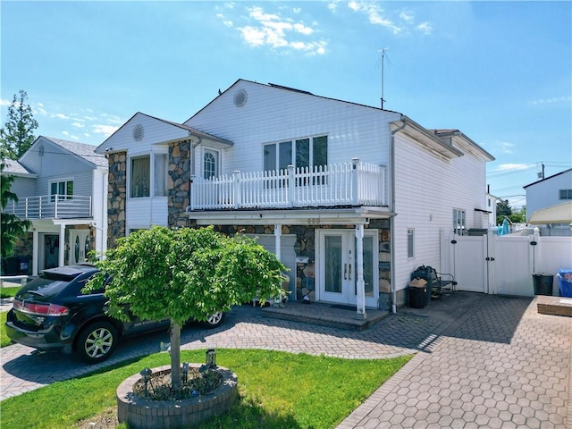 back of house featuring a balcony and french doors