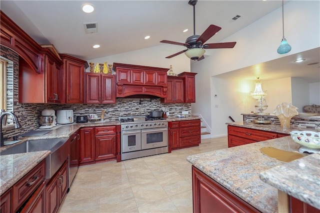 kitchen featuring hanging light fixtures, vaulted ceiling, tasteful backsplash, custom range hood, and stainless steel appliances