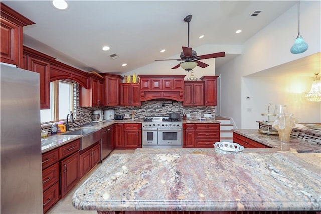 kitchen featuring light stone countertops, appliances with stainless steel finishes, decorative backsplash, pendant lighting, and lofted ceiling