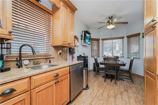 kitchen featuring ceiling fan, sink, light stone counters, stainless steel dishwasher, and backsplash