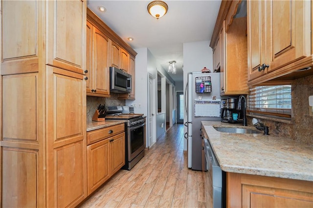 kitchen featuring plenty of natural light, light stone counters, sink, and appliances with stainless steel finishes