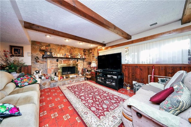 living room with a fireplace, beamed ceiling, a textured ceiling, and wooden walls