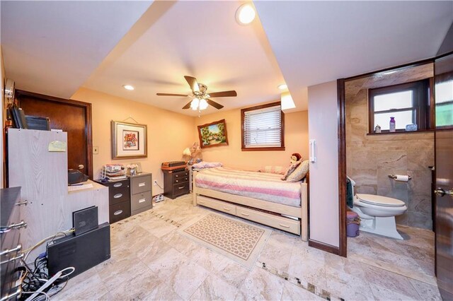 bedroom with multiple windows, ensuite bathroom, and ceiling fan