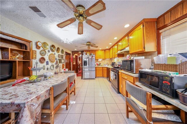 kitchen with ceiling fan, light tile patterned flooring, a textured ceiling, and appliances with stainless steel finishes