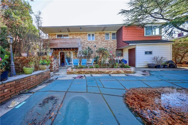 rear view of property with a patio area, a balcony, and a covered pool