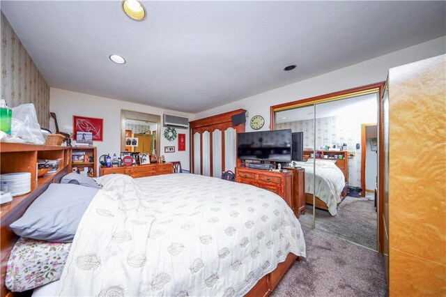 bedroom featuring a wall unit AC, multiple closets, and carpet floors