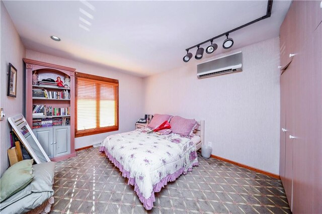 bedroom featuring dark colored carpet, an AC wall unit, and rail lighting