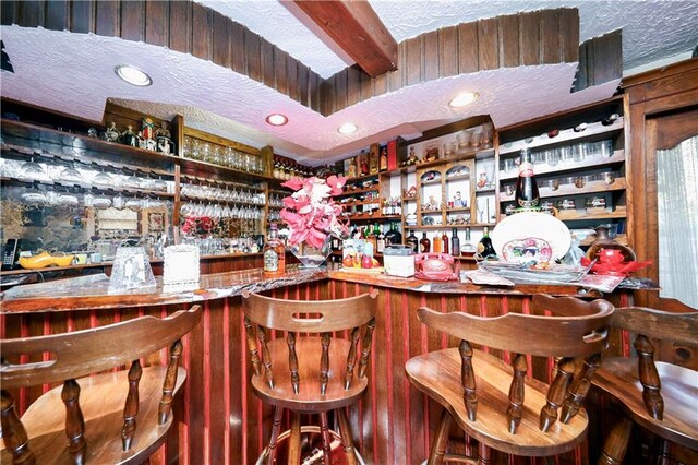 bar featuring beam ceiling and a textured ceiling