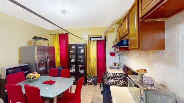 kitchen with decorative backsplash, appliances with stainless steel finishes, sink, and range hood