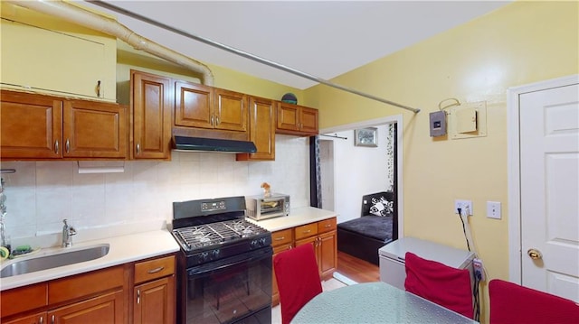 kitchen featuring black gas range, light hardwood / wood-style floors, tasteful backsplash, and sink