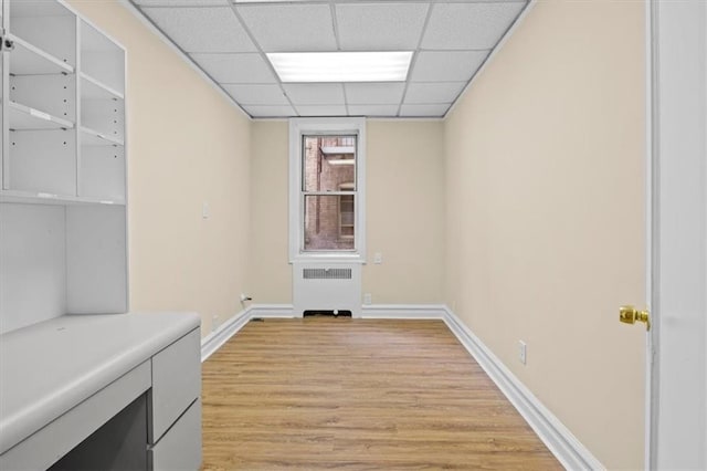 interior space with radiator, light hardwood / wood-style floors, and a drop ceiling