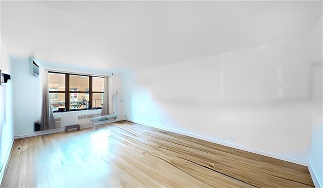 interior space with hardwood / wood-style flooring, an AC wall unit, and radiator