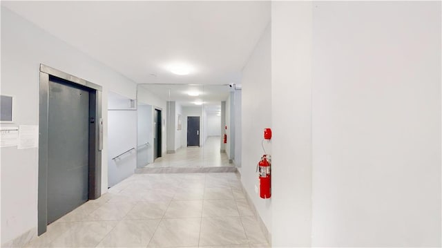 corridor featuring light tile patterned floors and elevator