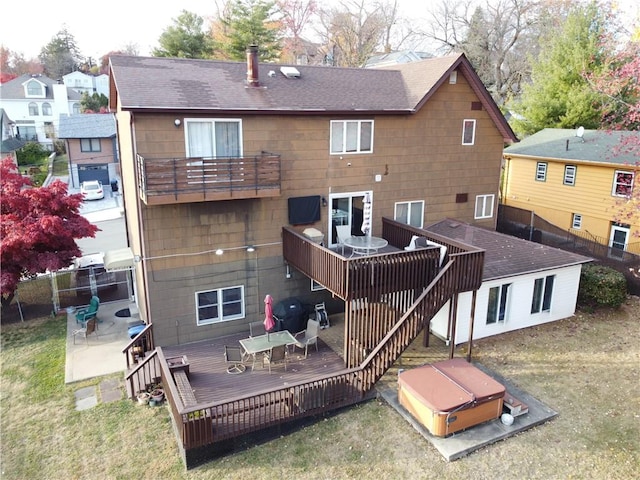 rear view of property with a wooden deck, a hot tub, and a balcony