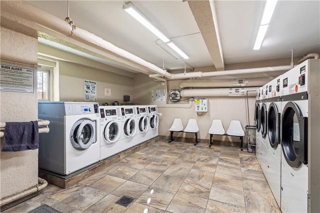 community laundry room with separate washer and dryer and stone finish floor