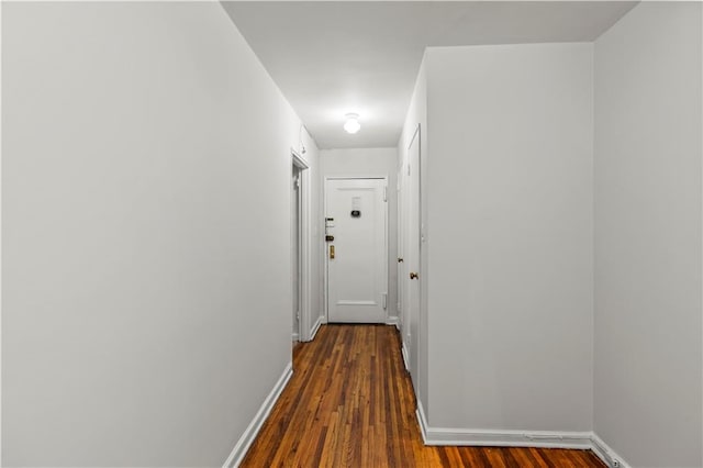 corridor with dark wood-type flooring and baseboards